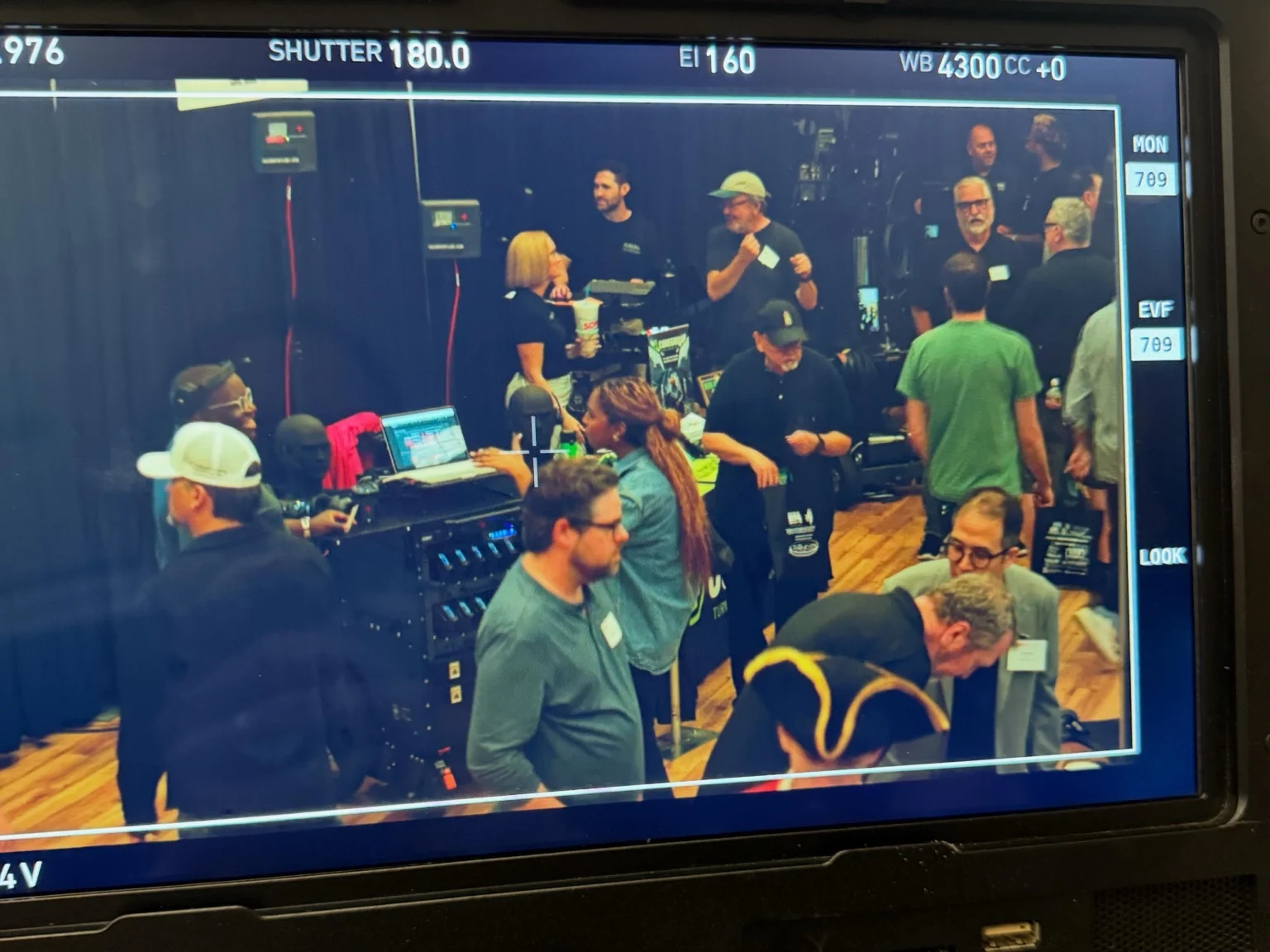 A production monitor showing a busy film set